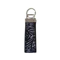 A backside photo of batik key fob in black driftwood pattern on a white color background