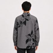 Person wearing a gray floral patterned shirt on a white background