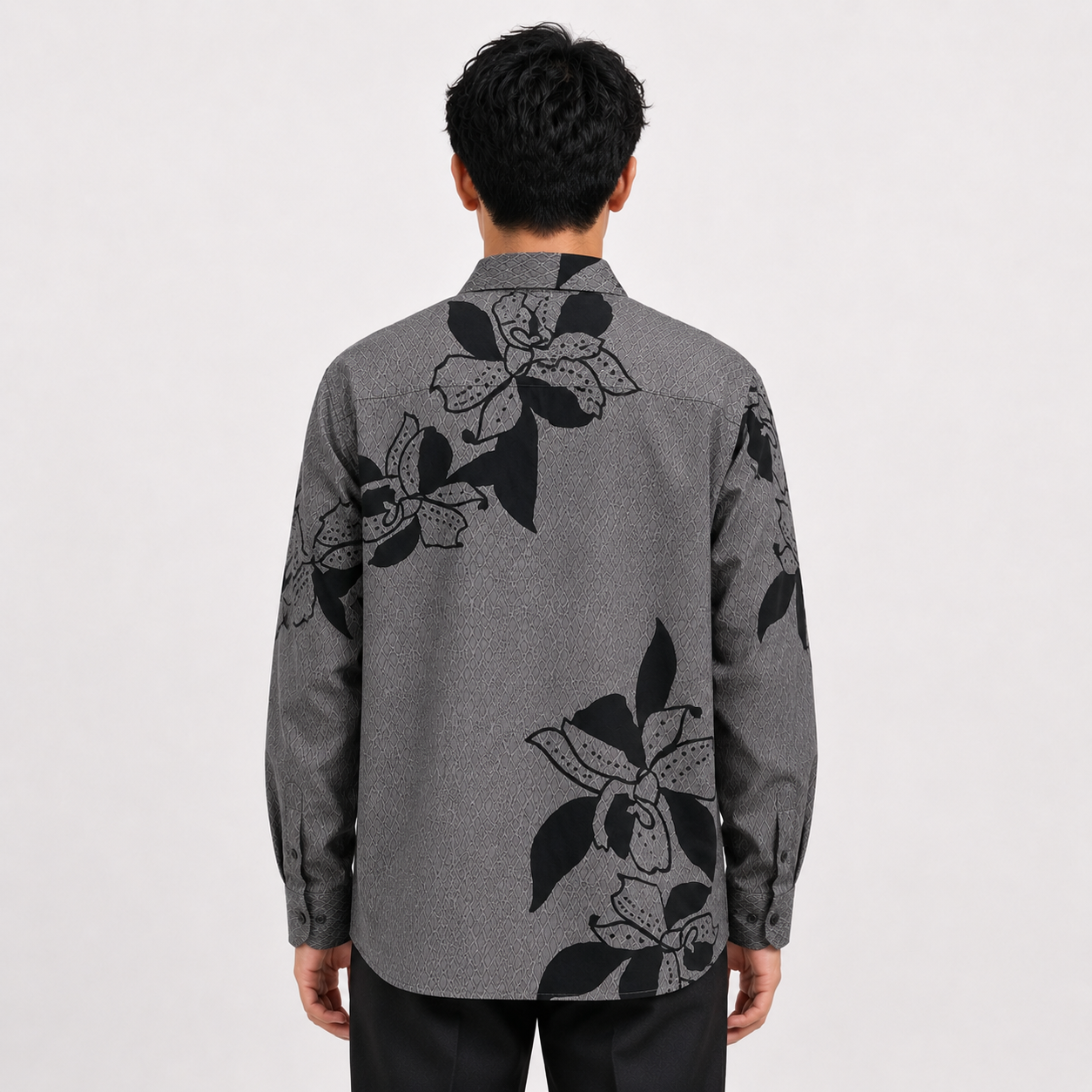 Person wearing a gray floral patterned shirt on a white background