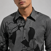 Man wearing a gray patterned shirt with black designs on a plain background
