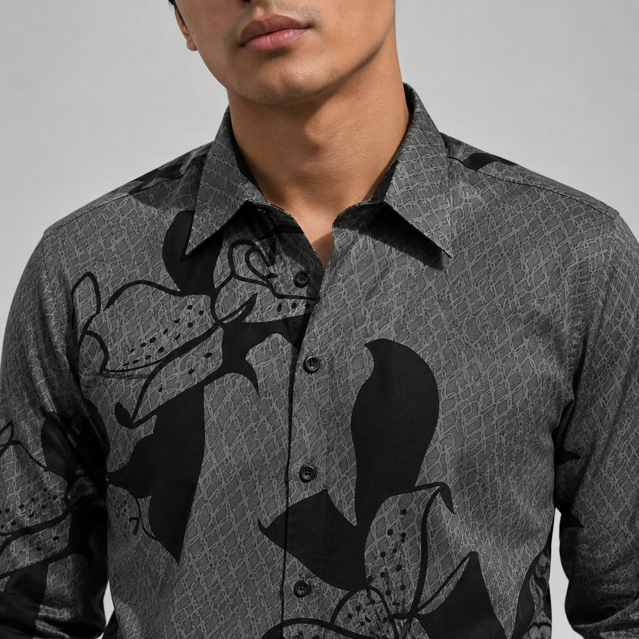 Man wearing a gray patterned shirt with black designs on a plain background