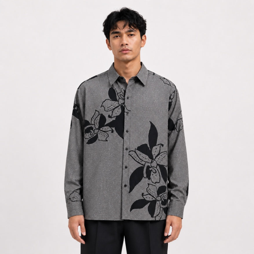 Man wearing a gray shirt with black floral patterns on a white background