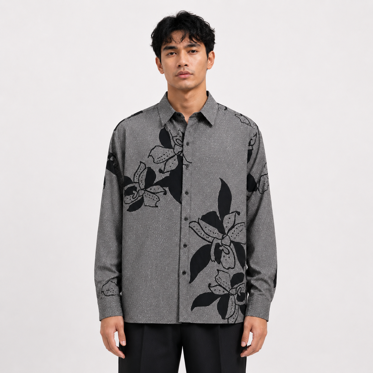 Man wearing a gray shirt with black floral patterns on a white background