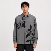 Man wearing a gray shirt with black floral patterns on a white background