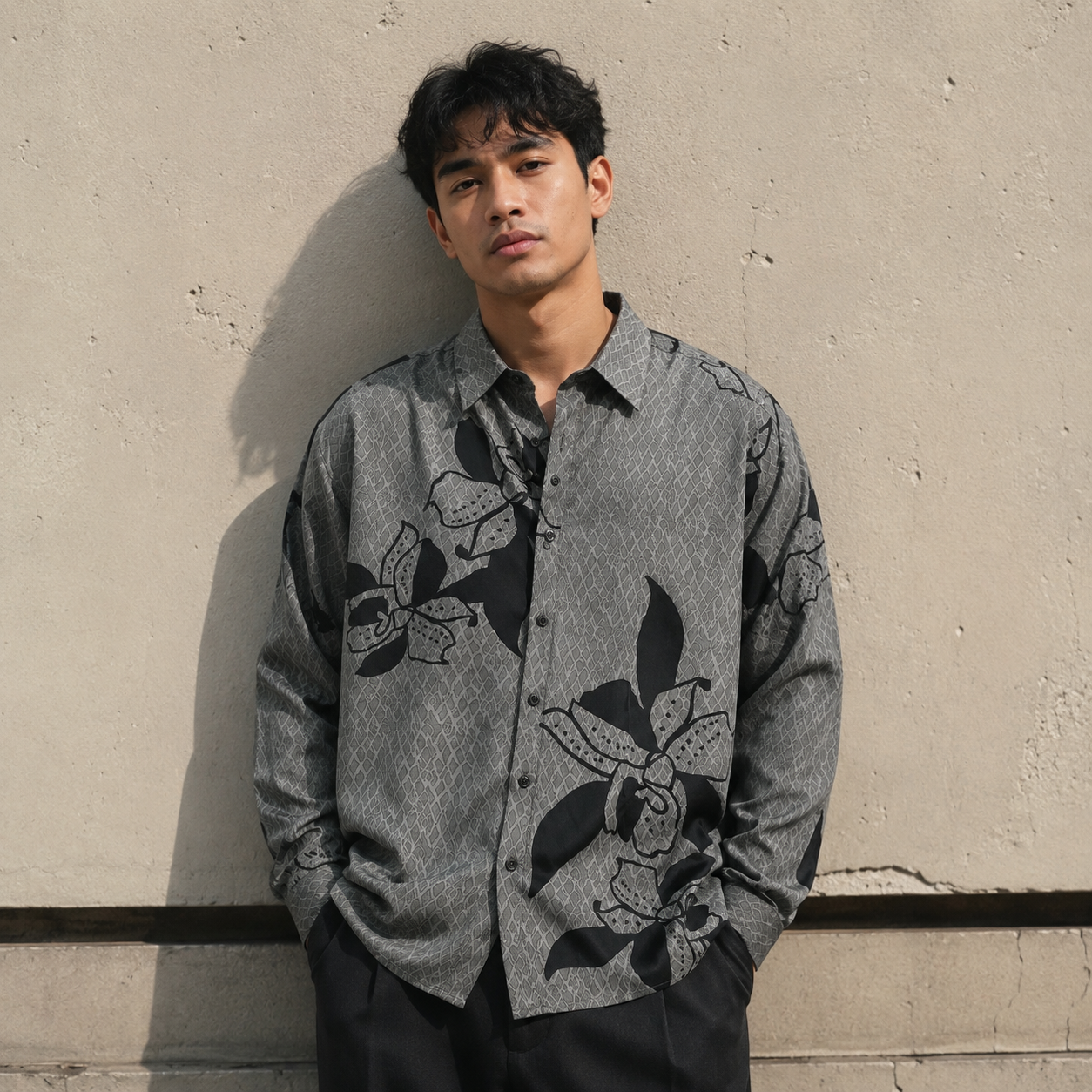 Man wearing a gray floral shirt against a beige wall