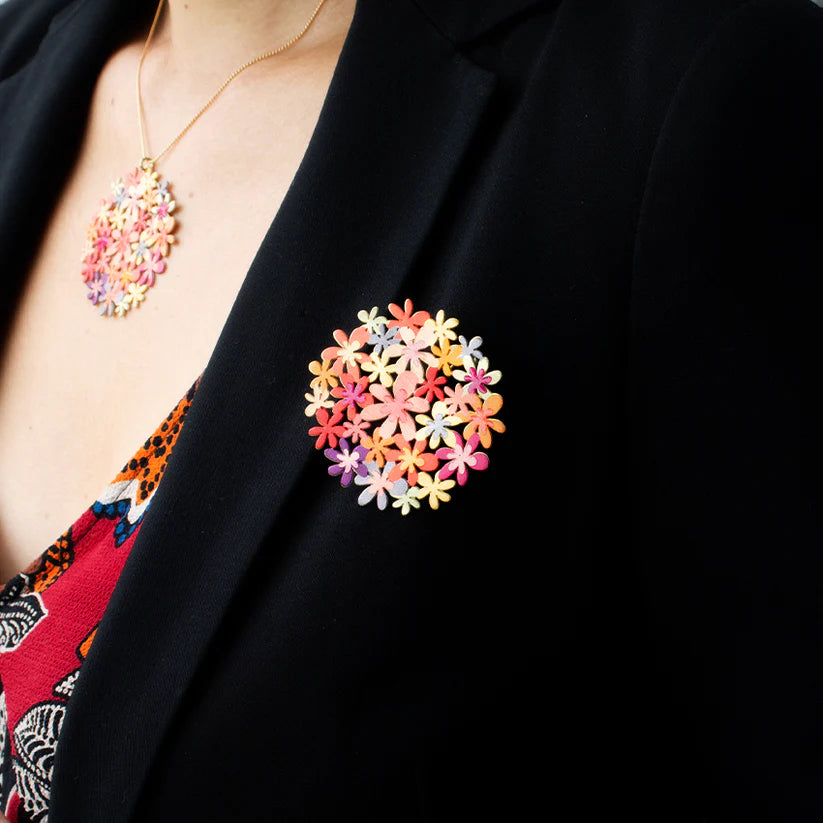 Colorful floral brooch on a black blazer with matching necklace