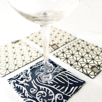 batik coasters made from batik remnants that are reversible, in the pattern blue nautical fern with a glass and against a neutral background