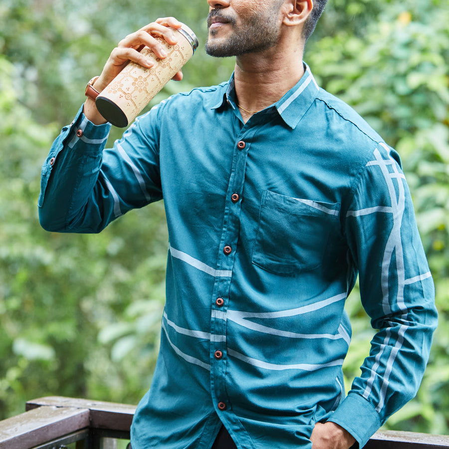Man sipping his tumbler from Batik Boutique wearing batik long sleeved shirt in Forest Green colorways, handprinted in Malaysia.