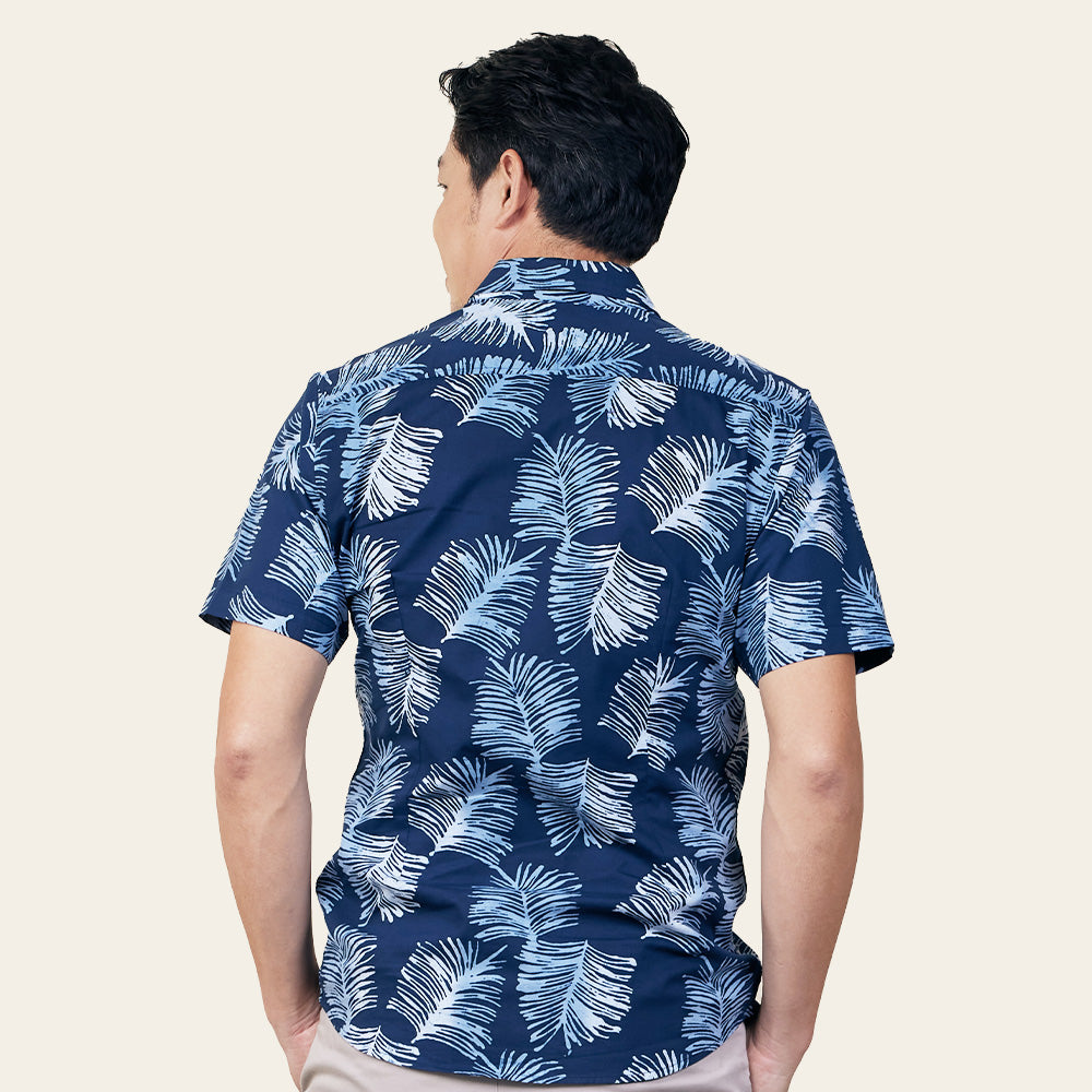 a photo of a model with his back facing the camera against a neutral background while wearing batik shirt in navy sawit