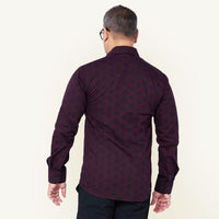 Man posing with his back to the camera, showcasing the details of his batik shirt in the pattern garnet firework
