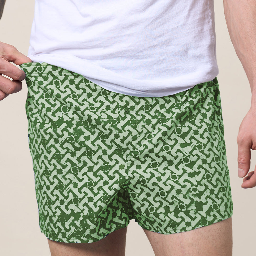 A model is wearing green batik boxer in forest arabesque pattern. He showing front part of it. 