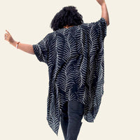 a woman posing with her back on the camera in front of a white surface while wearing batik kimono in the pattern black fern