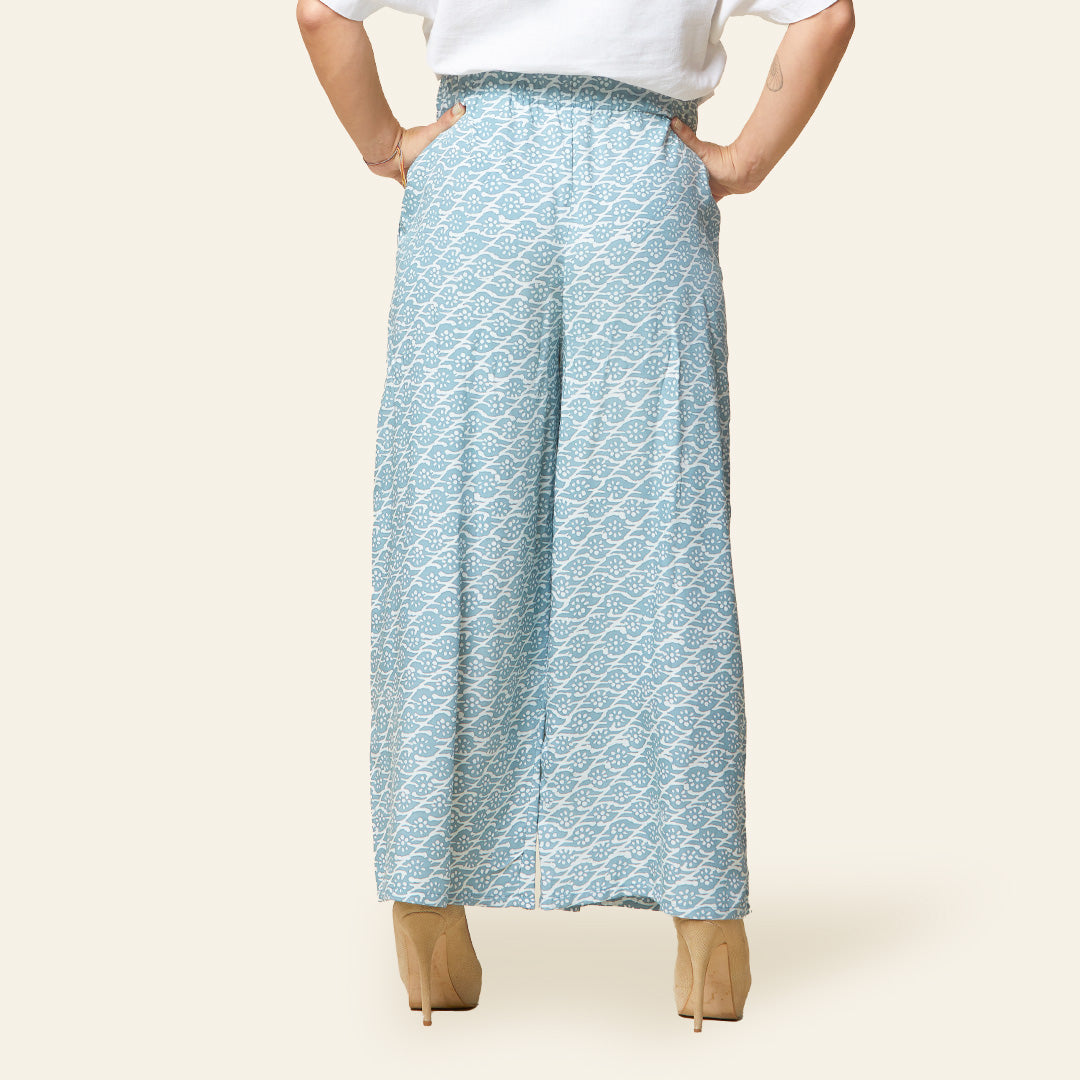 a women standing by a white background styling batik wide leg pants in mint bloom 