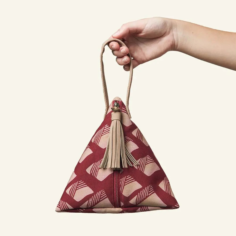 a photo showcasing a bag uniquely shaped like a ketupat in the pattern crimson red in front of a neutral background