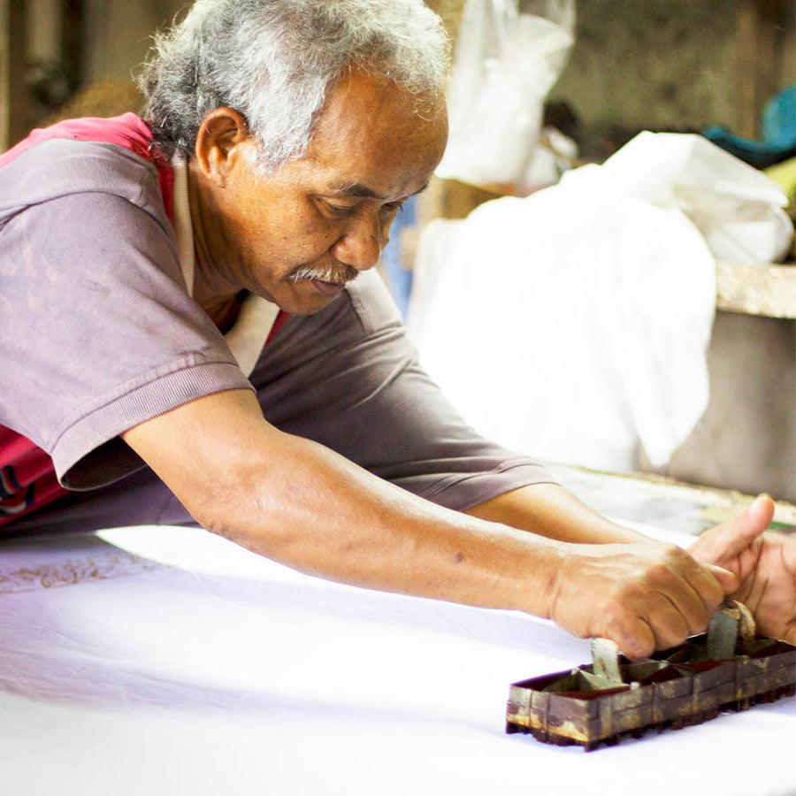 Artisan working with hands using batik blocks in his workshop celebrating Malaysian crafts, in collaboration with Batik Boutique.