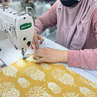 A seamstress is sewing batik remnant in golden pineapple pattern
