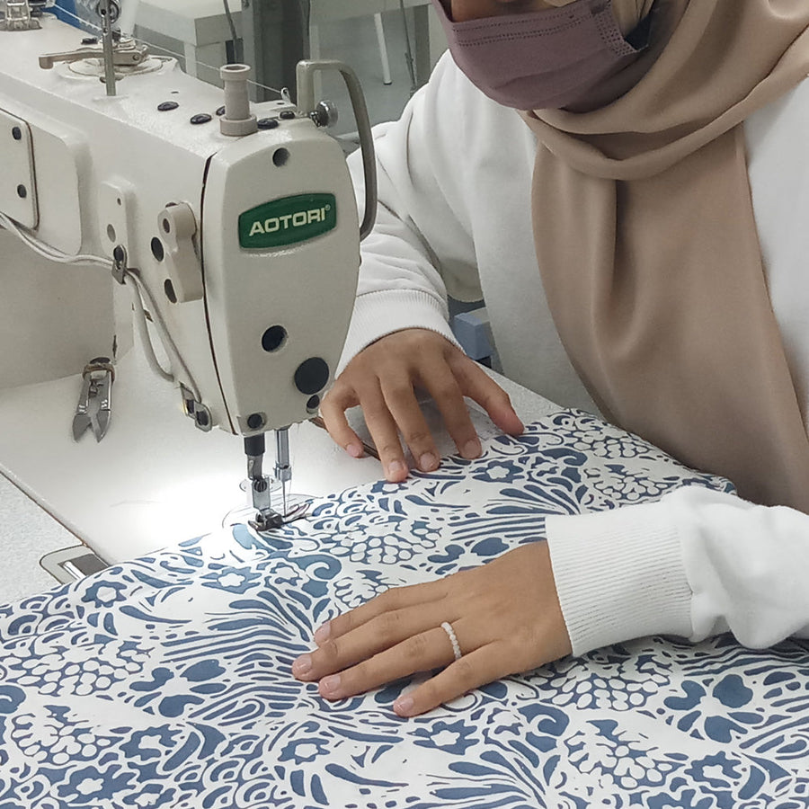 a seamstress is sewing batik fabric in grey peony print