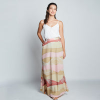 Full view of female model wearing long flair pink batik skirt and white camisole.