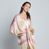 Woman in pink, tan, white hand-drawn batik kimono tied at waist, part of Raya 2023 collection.