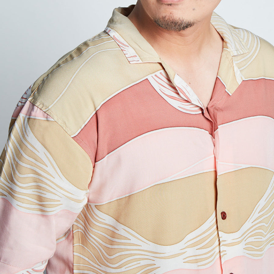 A close up photo of man wearing batik cuban shirt in pink and neutral color combo.