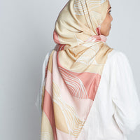  A back view of a woman wearing a multi-colored batik scarf as a hijab from from cotton silk in tan, pink, and white colors from the Bukit Collection from Batik Boutique.