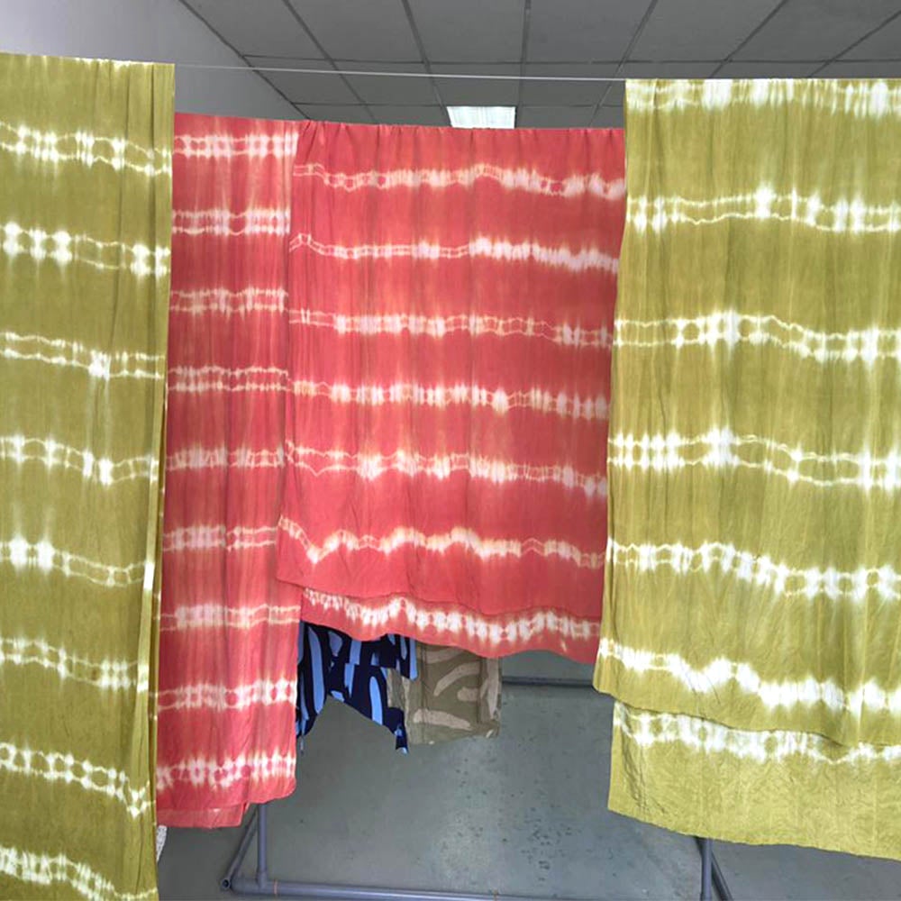 Artisanal Shibori fabric drying in batik workshop in Malaysia, both in green and coral color combinations.
